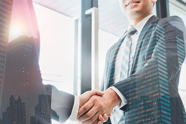 Double exposure of two businessmen reaching an agreement and making handshake with abstract construction building - Greeting and dealing real estate business concepts.