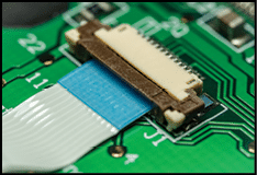 Macro photo of a flat ribbon cable and connector on a green printed circuit board (PCB)