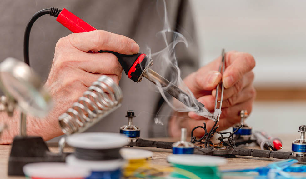 Closeup view of man hands during quadcopter repairing process using soldering iron for wires