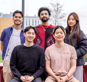 Five people are posing for a picture in front of a building. AI generated content
