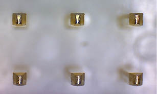 A row of small, golden rings are lined up on a white surface. AI generated content