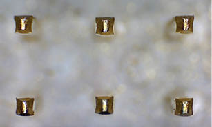 A row of gold nails are embedded in a white surface. AI generated content