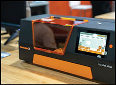 A black and orange machine with a screen on a wooden table. Description generated by AI