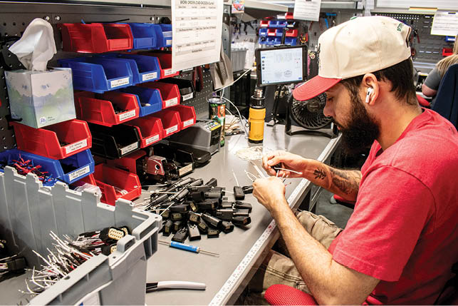 A man wearing a red shirt is working on a computer. Description generated by AI