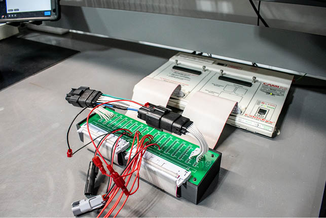 A computer circuit board with wires and a green box. Description generated by AI