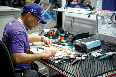 A man wearing a blue hat is working on a project. Description generated by AI