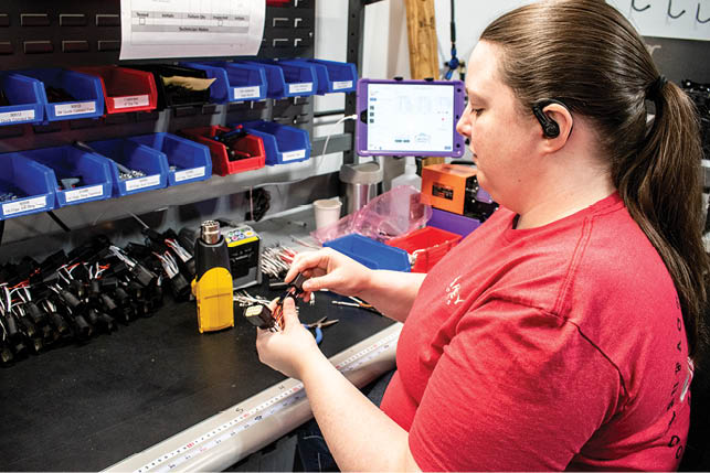 A woman in a red shirt is working on a project. Description generated by AI