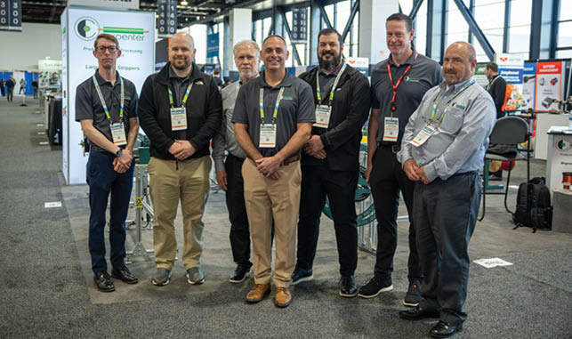 A group of men wearing name tags and shirts pose for a picture. Description generated by AI