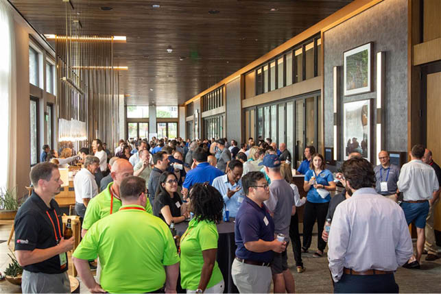 A large group of people are standing in a room. Description generated by AI