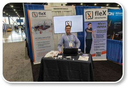 A man standing in front of a table with a laptop and a sign that says “Flex". Description generated by AI