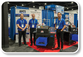Three men in blue shirts standing in front of a display. Description generated by AI