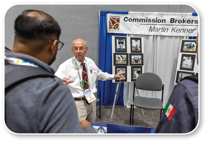 A man wearing a red tie is talking to two other men. Description generated by AI