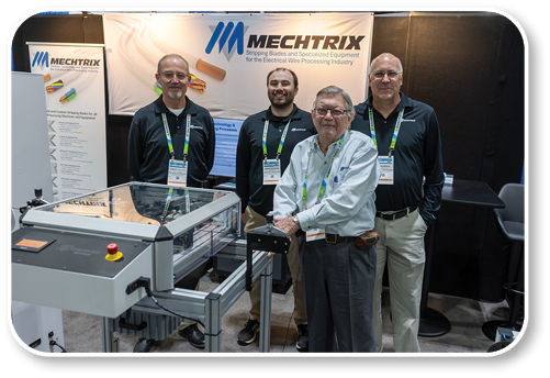 Four men standing in front of a machine. Description generated by AI