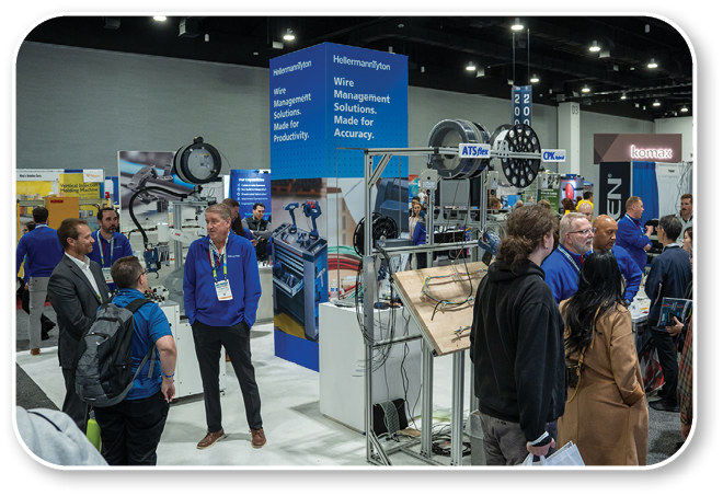 A group of people are standing in a room with a display of machinery. Description generated by AI