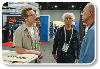 Three men are standing in a room. Description generated by AI