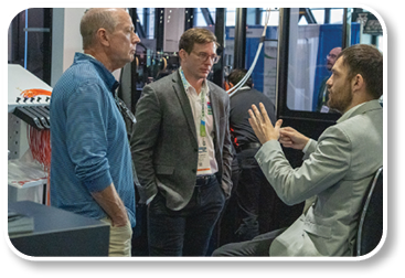 Three men are standing in a room. Description generated by AI