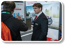 A man in a suit and tie is standing in front of a display. Description generated by AI