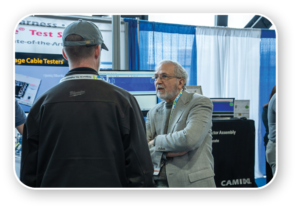 Two men are talking in front of a computer. Description generated by AI