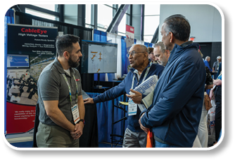 A man in a blue shirt is talking to two other men. Description generated by AI