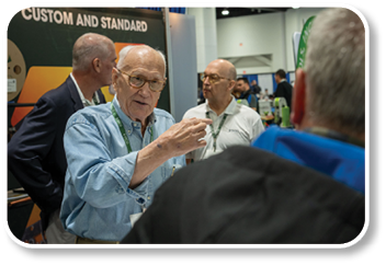 A man wearing a blue shirt is talking to another man. Description generated by AI