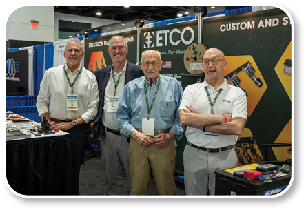 Four men standing in front of a booth. Description generated by AI