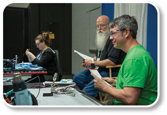 A man in a green shirt is reading a piece of paper. Description generated by AI