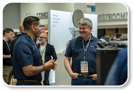 Two men wearing blue shirts are talking to each other. Description generated by AI